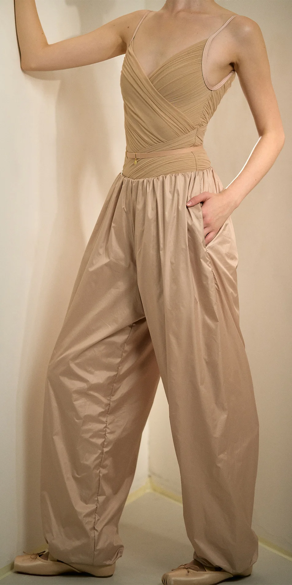Womens lightweight baggy pants in light beige front crop shot hand on the wall